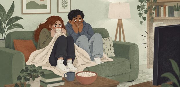 Two people sit on the couch watching a scary movie.